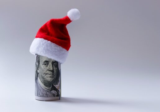 Santa's red cap is worn on a hundred-dollar bill rolled up with a picture of President Franklin. Free space for copying.