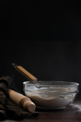 Bakery items - flour and eggs on dark background, healthy basic baking ingredients. Space for text