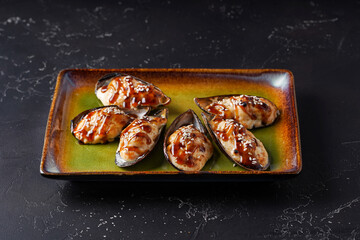Baked mussels with cheese on a plate. On a dark background. 