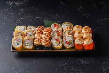 Set of tempura California rolls with crab, baked California roll with shrimp, baked Canada roll with eel on a dark background.