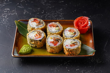 Roll with eel, avocado, salmon, cream cheese, tempura, Panko breadcrumbs. On dark background.