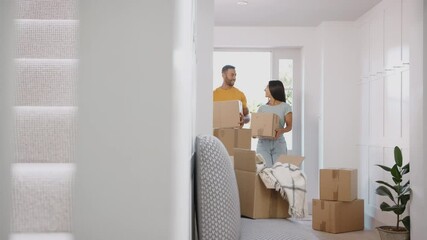 Camera tracks across hallway to show excited couple hugging as they move into new home surrounded by boxes - shot in slow motion