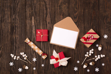 Holiday card - empty letter, Christmas decorations, gift boxes and candy canes on dark wooden background.