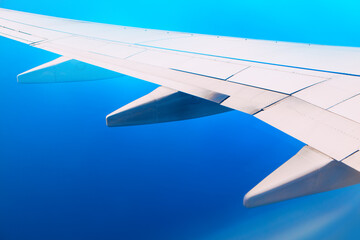 White airplane wing in flight . Flying over the blue sea