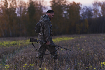 Male hunter in camouflage clothes ready to hunt with hunting rifle