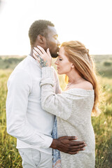 Touching moment african-american husband is touching with care tummy of his beautiful pregnant wife and kissing her forehead