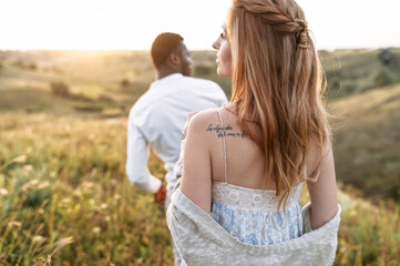 Back view of couple in love walking through summer meadow