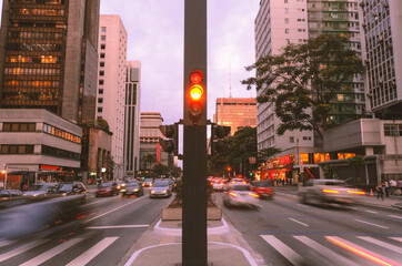 Paulista Avenue in São Paulo, Brazil. Movement of cars in the late afternoon. In the middle of the avenue, a traffic light, buildings and a pedestrian crossing in perspective.