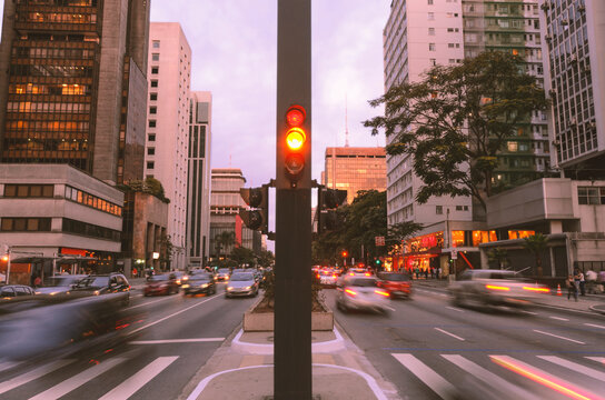Paulista Avenue in S&atilde;o Paulo, Brazil. Movement of cars in the late afternoon. In the middle of the avenue, a traffic light, buildings and a pedestrian crossing in perspective.