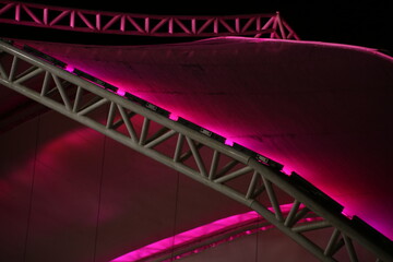 Close up of the metal beams and with pink light illuminated tarp of an open podium