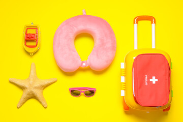 Flat lay composition with child beach accessories and first aid kid on color background. Travel...