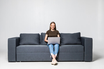Obraz premium A pretty woman wearing casual clothes with laptop sit on sofa isolated on white background
