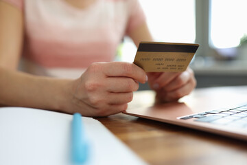 Woman holds plastic credit bank card and makes online purchases. Safe internet payments concept