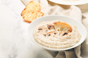 Bowl of tasty mushroom cream soup on light background