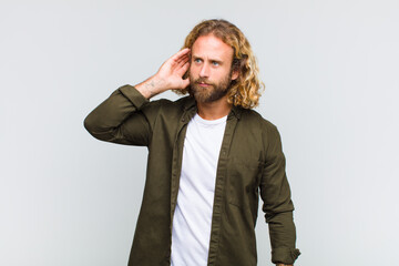 blonde man looking serious and curious, listening, trying to hear a secret conversation or gossip,...