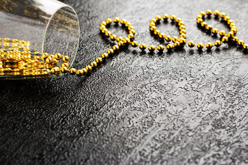 Glass with gold beads on a black background.