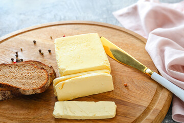 Butter, knife and bread on wooden board