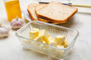 Diced butter in glass dish with garlic and toasts on white table