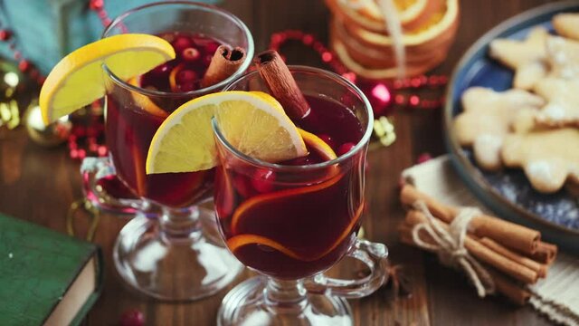 Fragrant, hot punch or mulled wine for Christmas in a tall cup on a background of gifts, toys and fir branches. Hot winter drink of wine with spices and fruit.