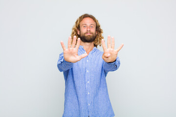 blonde man smiling and looking friendly, showing number nine or ninth with hand forward, counting...