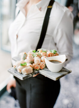 Waitress carrying platter of rice paper rolls and dipping sauce