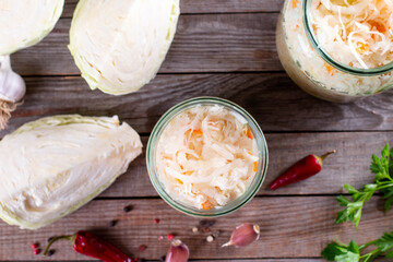 Sauerkraut in glass jars on wooden table. Fermented canned vegetables food concept. Top view