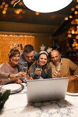 Happy family greeting their family and friends with a champagne glass, on New Year's eve using a...