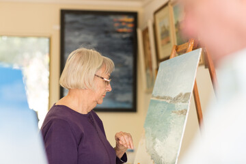 Elderly woman in art class with painting