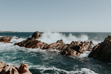 Waves crashing on rock formations just off coastline