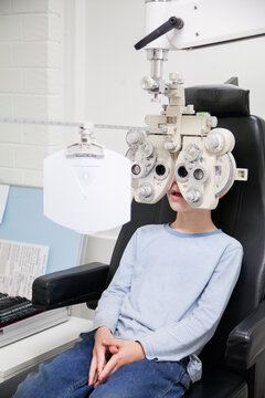 Young boy looking through phoropter during eye examination