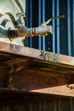 Outside rain water tap on rusty, moss covered tank stand