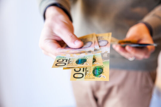 Man holding out fifty dollar notes