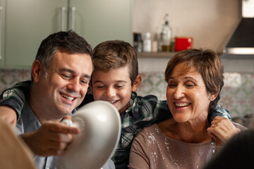 Portrait of son, grandson and grandmother sitting at the the Christmas Thanksgiving table, looking at the delicious food. Soup, turkey and red wine. Celebrating being together, Christmas Holidays.