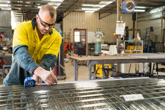 A tradesman measuring and marking screening laid on a workbench