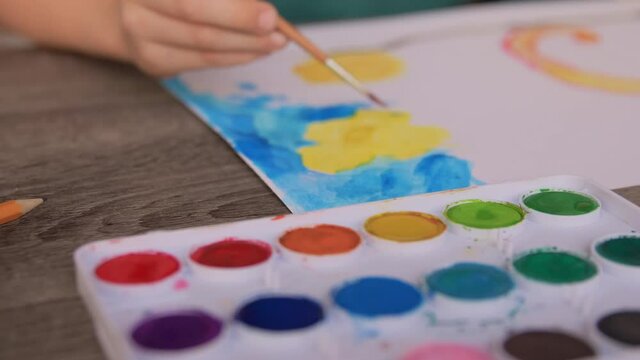 childhood, hobby and art concept - little boy drawing picture with colors and brush at home