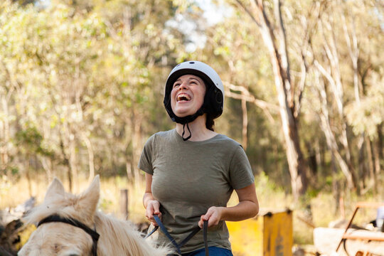 Person riding horse laughing as she canters outside