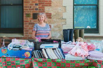 senior woman standing behind her bric a brac stall at a country market