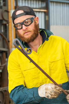 A tradesman wearing high vis clothing examining the bends in a curved steel rod