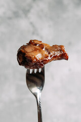 BBQ chicken wing in spicy sauce on a fork