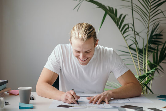 Happy designer working at a desk with indoor plant behind