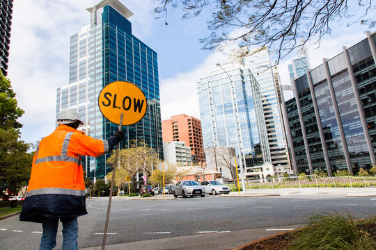 worker wearing high vis holding a slow sign