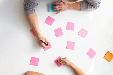 Brainstorming ideas on blank pink notes from overhead