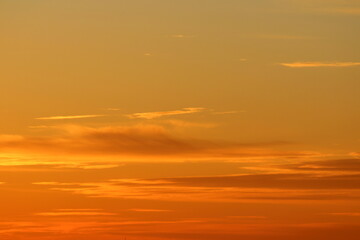 Sun below the horizon and clouds in the fiery dramatic orange sky at sunset or dawn backlit by the sun. Place for text and design