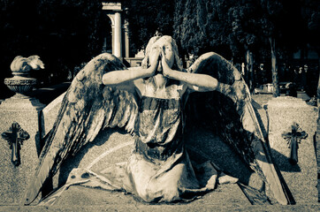 La statua di un angelo con le mani giunte su una tomba del cimitero monumentale di Staglieno a...