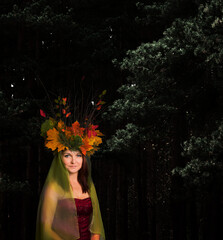 a woman in a crown of branches and leaves stands in a dark forest. forest queen of autumn