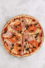 Pizza with mushrooms and ham on a light background, top view