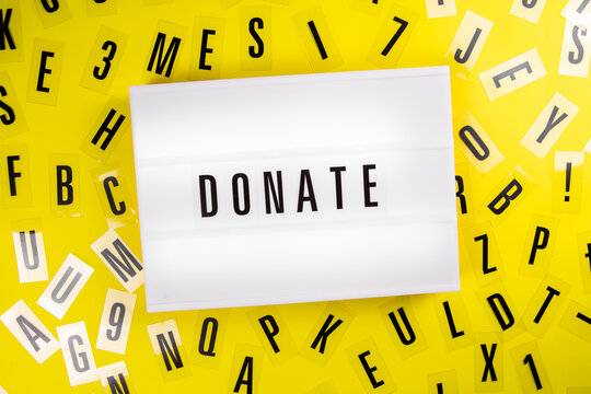 Donate word on lightbox on scattered letters background of plastic alphabet. charitable foundation Announcement , call for donations, compassion, money transfers to charity organizations, philanthropy
