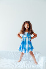 Portrait of a beautiful little curly girl in a blue dress