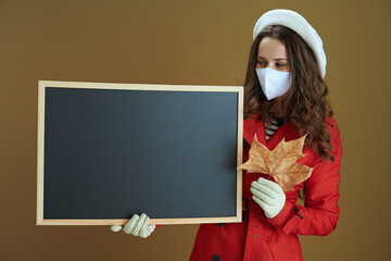 woman showing blank blackboard isolated on bronze background
