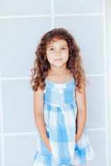 Portrait of a beautiful little curly girl in a blue dress